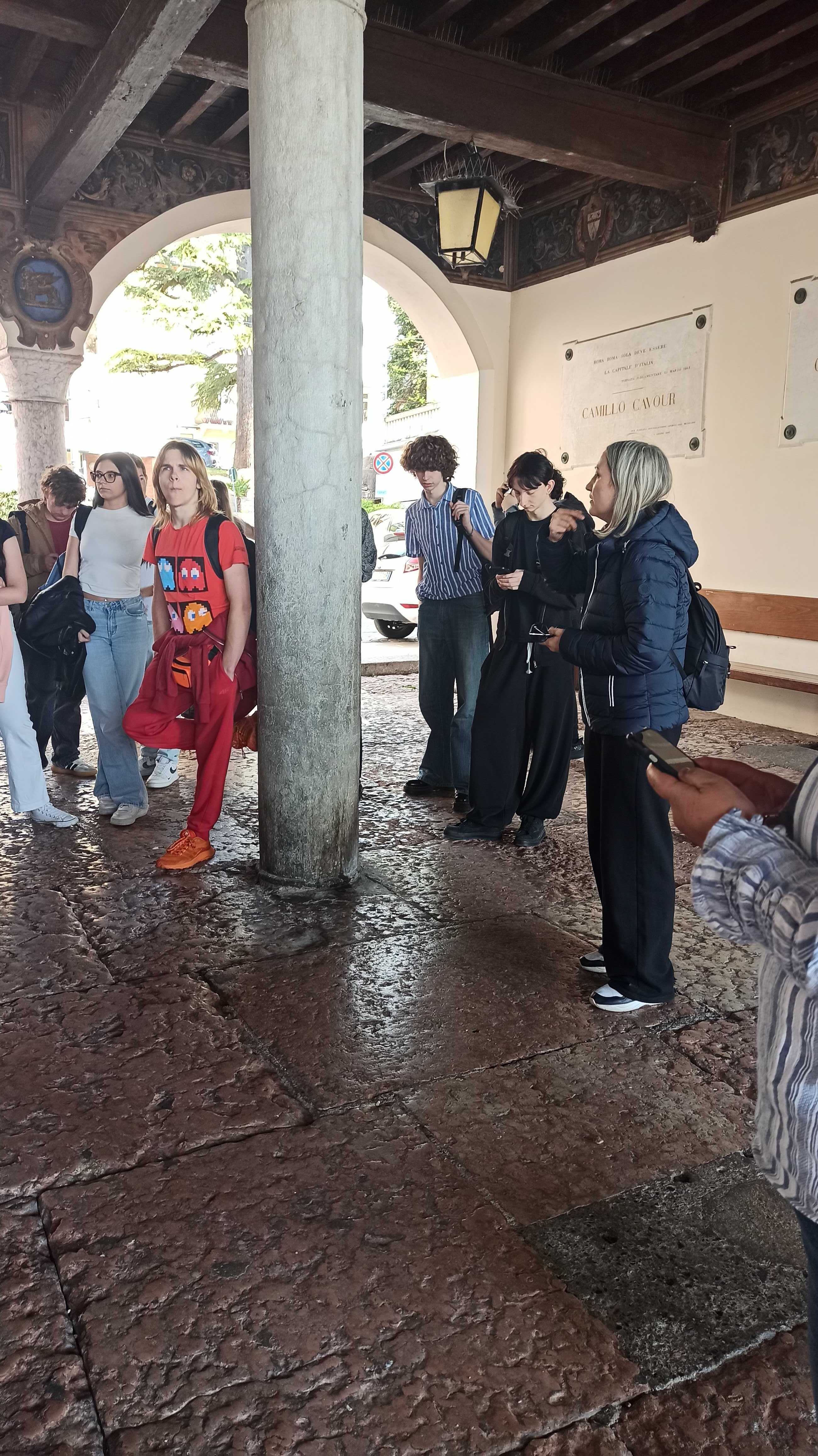 Coordinator guiding students under a historic arcade