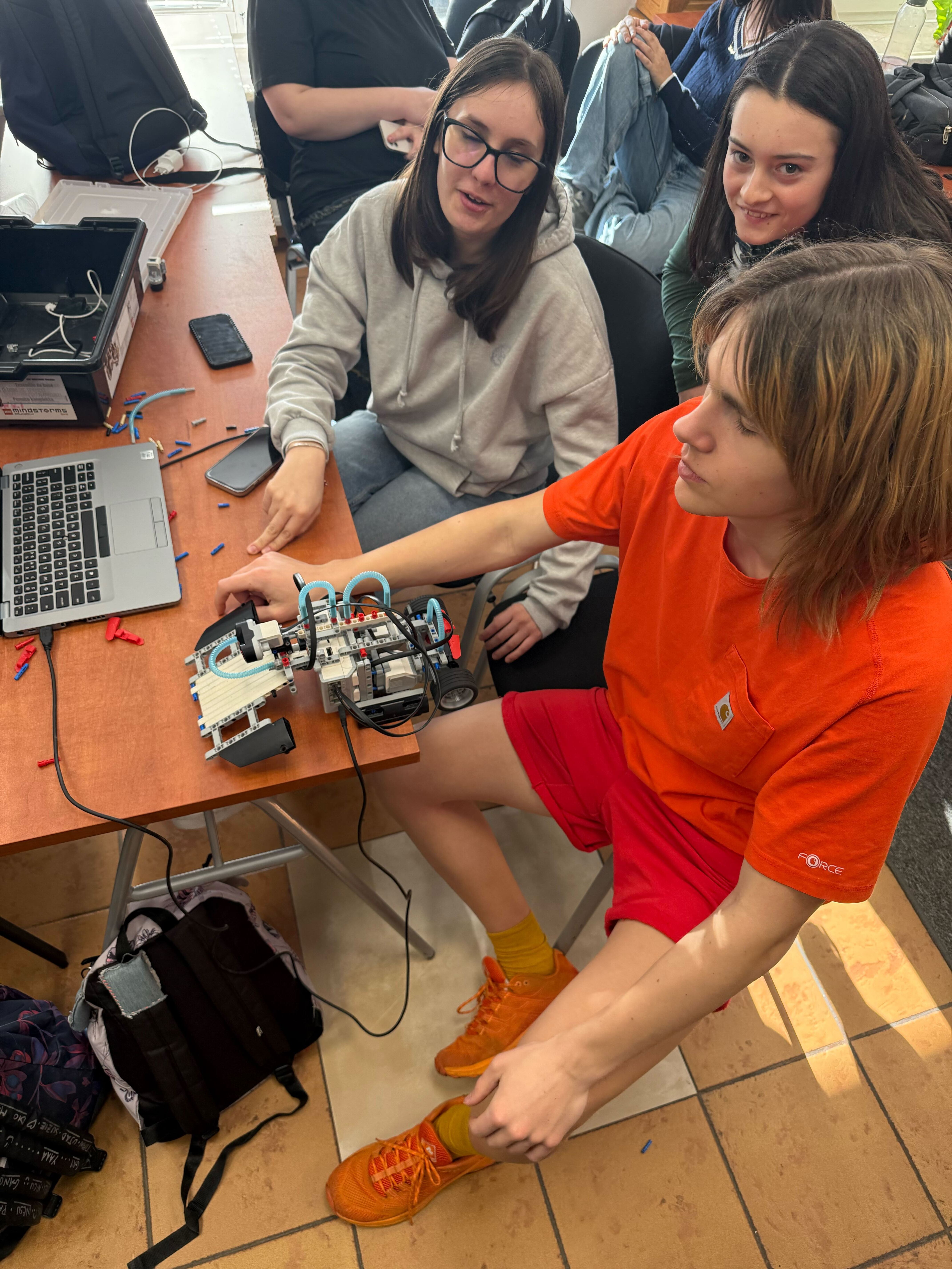 Students programming a LEGO Mindstorms robot on a laptop