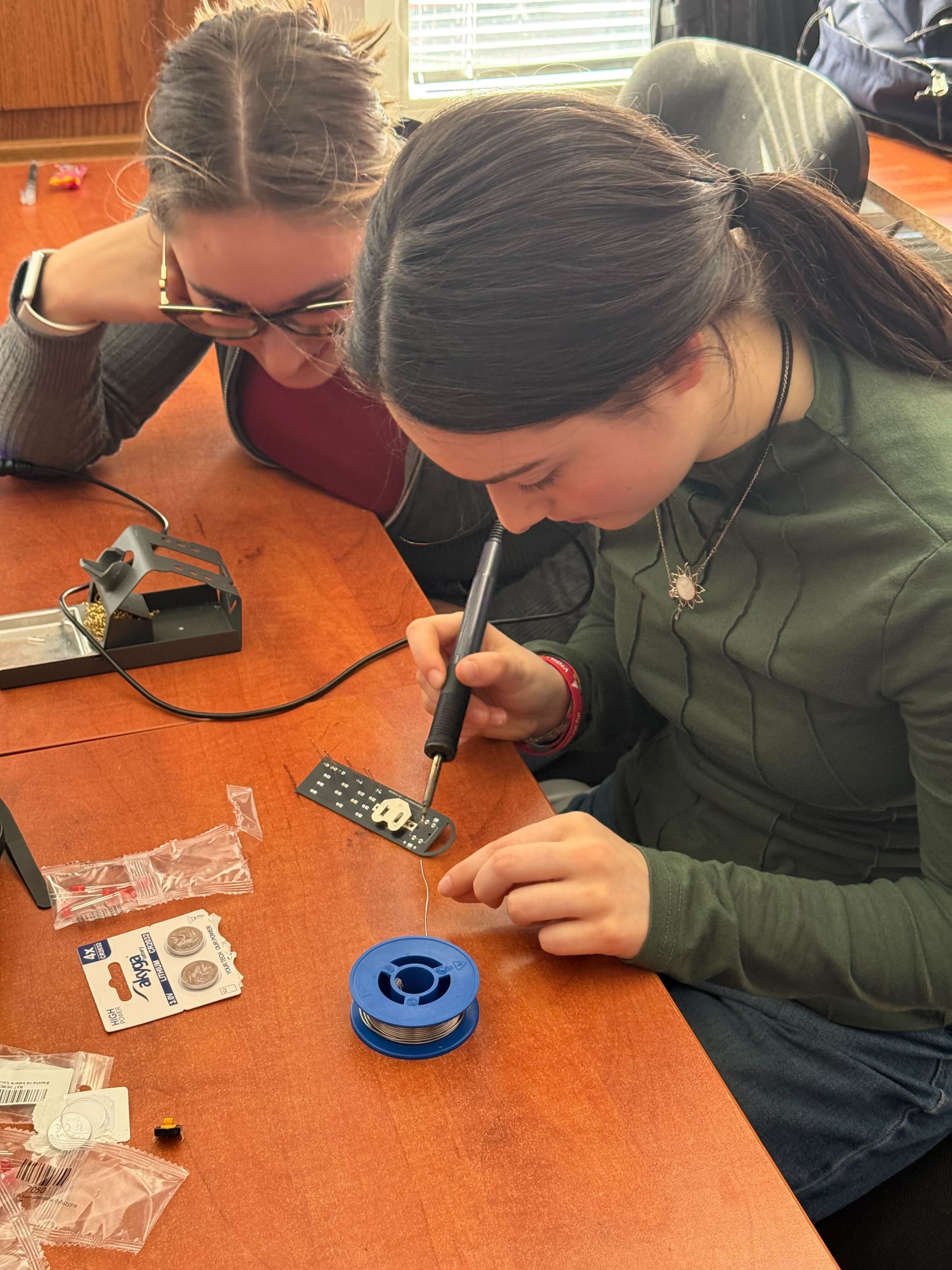 Two students closely soldering a circuit board