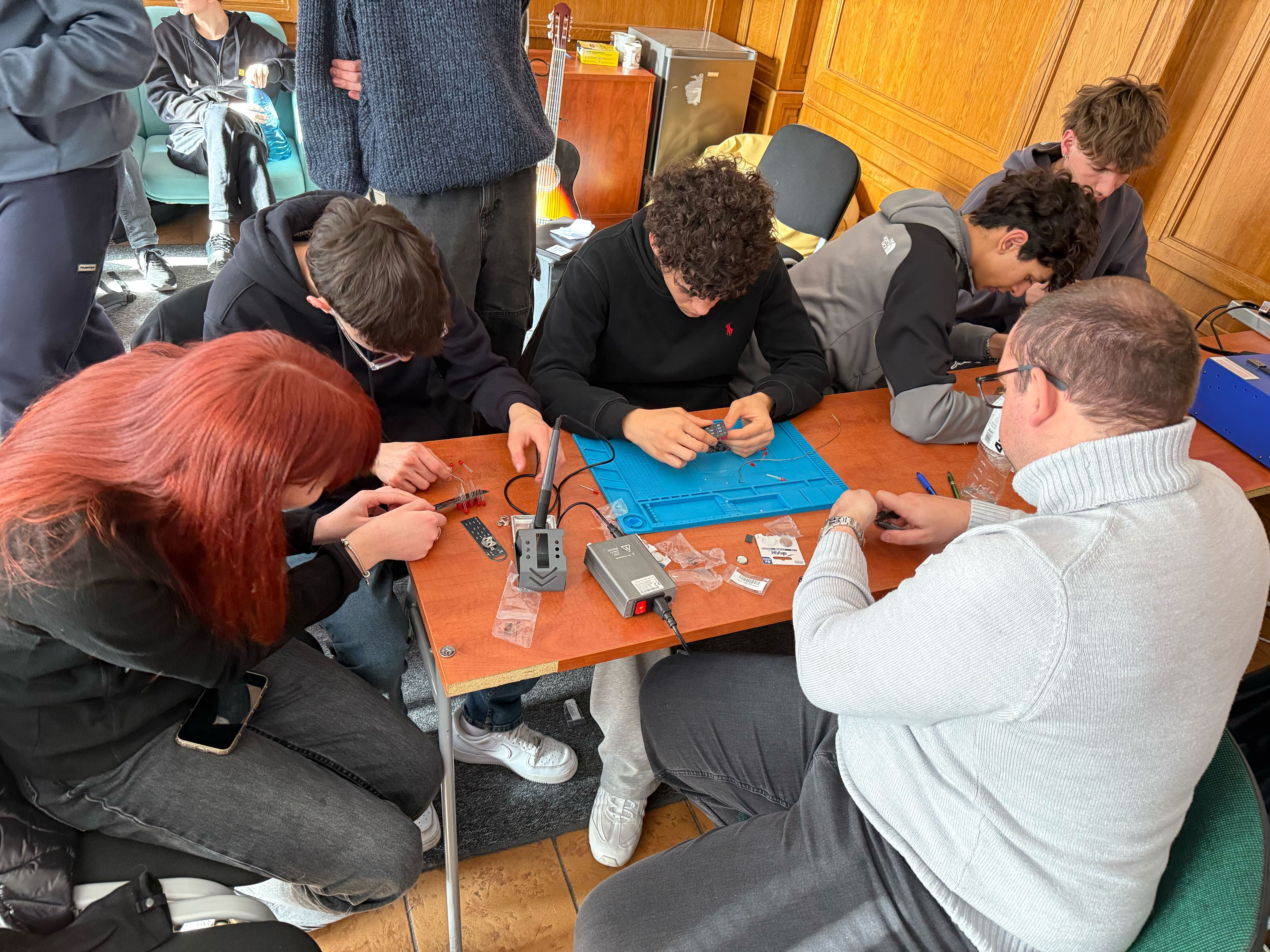 Students soldering electronics with a teacher
